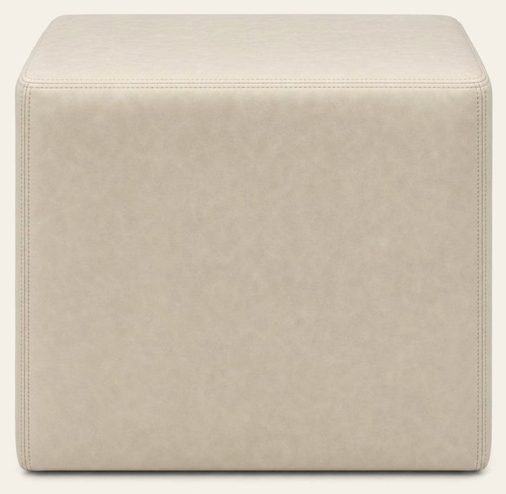 Cream square ottoman with cube silhouette and linen-like upholstery.