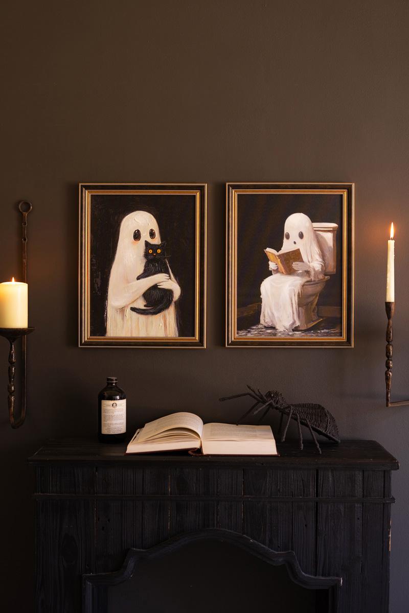 Pair of framed Halloween ghost paintings hung above a dark console with candles and a book - ghost wall art by Kalalou - Whats New Furniture Portland OR