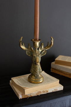 Antique Gold Deer Head Taper Candle Holder styled on a stack of antique books with a lit taper - gold deer candle holder by Kalalou - Whats New Furniture Portland OR