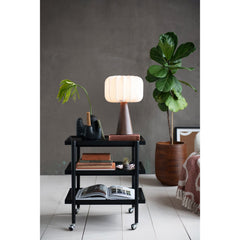 Wood finish pleated shade lamp lit on a shelf beside a potted plant in a grey-walled Portland room - Whats New Furniture Portland OR