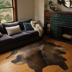 Brown cow hide area rug with natural markings and irregular hide outline.