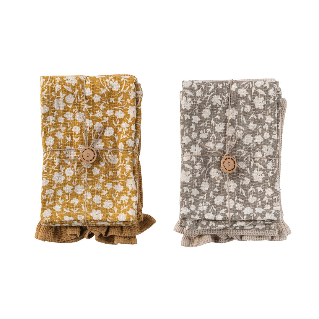 Mustard floral and taupe cotton tea towels folded and tied with a wood button