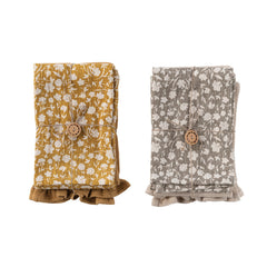 Mustard floral and taupe cotton tea towels folded and tied with a wood button