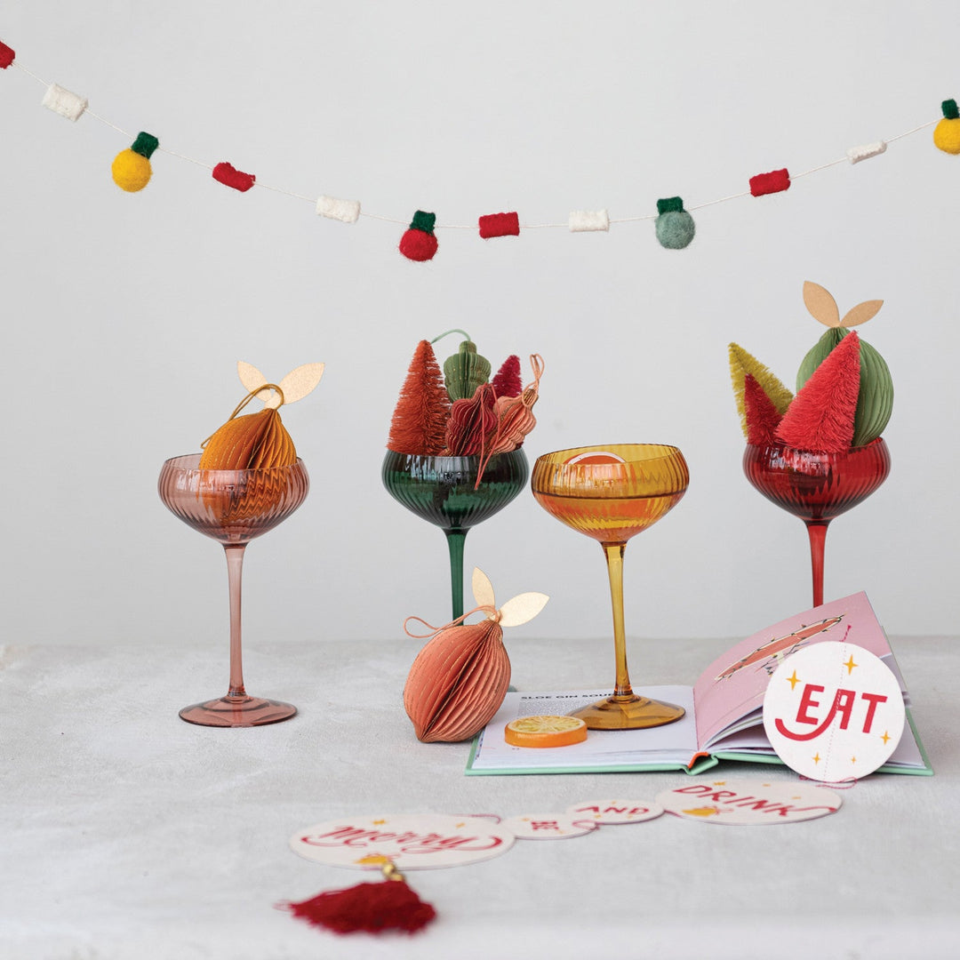 Four colored coupe glasses styled under a felt holiday garland with paper ornaments - Creative Co-Op stemware - Whats New Furniture Portland
