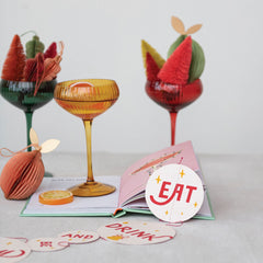 Jewel tone fluted coupe glasses styled with bottle brush trees and holiday ornaments on a party table in a Portland home - Whats New Furniture