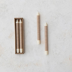 Pair of tan horizontal striped taper candles beside the retail box