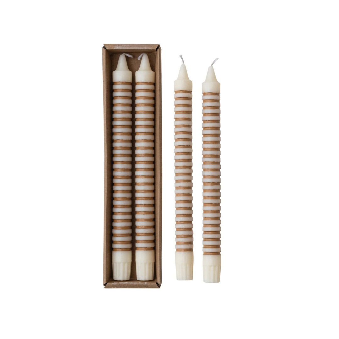 Tan striped taper candles in their box beside the pair of candles