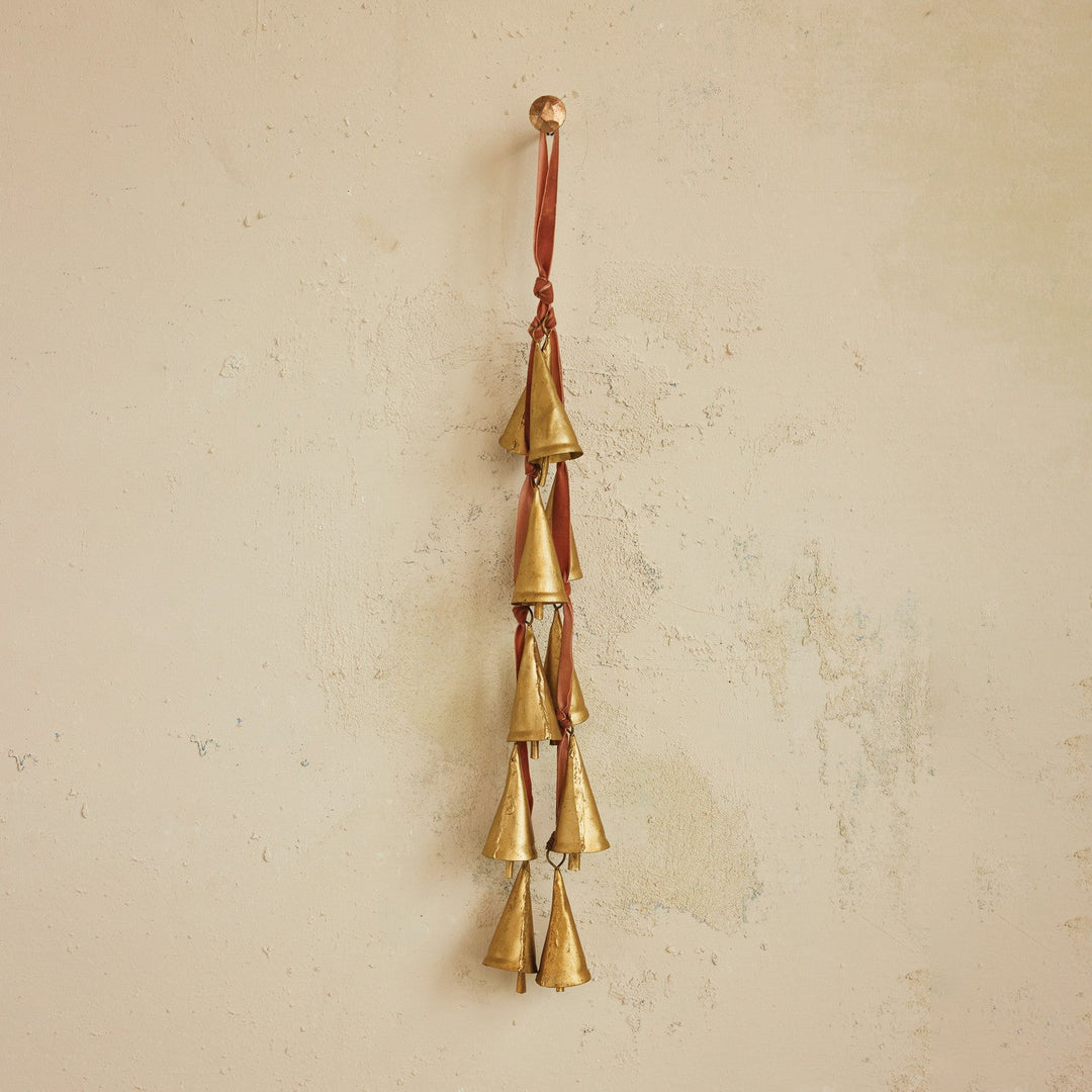 Brass bell door hanger on rose velvet ribbon styled hanging against a warm plaster wall in a Portland entry - Whats New Furniture