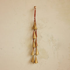 Brass bell door hanger on rose velvet ribbon styled hanging against a warm plaster wall in a Portland entry - Whats New Furniture
