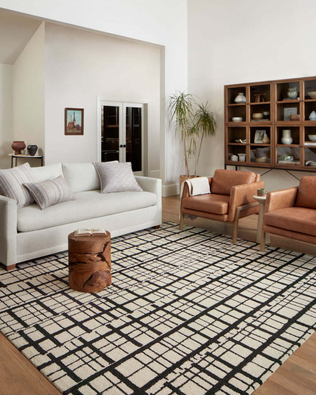 Black and ivory Polly rug styled in a bright living room with a white sofa and leather chairs - Whats New Furniture