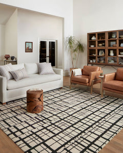 Black and ivory Polly rug styled in a bright living room with a white sofa and leather chairs - Whats New Furniture