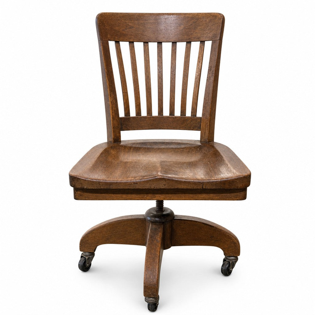Medium oak brown vintage bankers chair with spindle back and saddle seat by Heywood Wakefield
