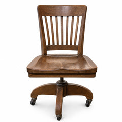 Medium oak brown vintage bankers chair with spindle back and saddle seat by Heywood Wakefield