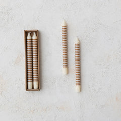 Pair of tan horizontal striped taper candles beside the retail box