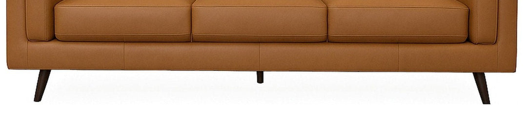 Close-up of the upholstered base band and splayed tapered legs on the camel Eager leather sofa - What&