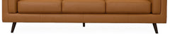 Close-up of the upholstered base band and splayed tapered legs on the camel Eager leather sofa - What&