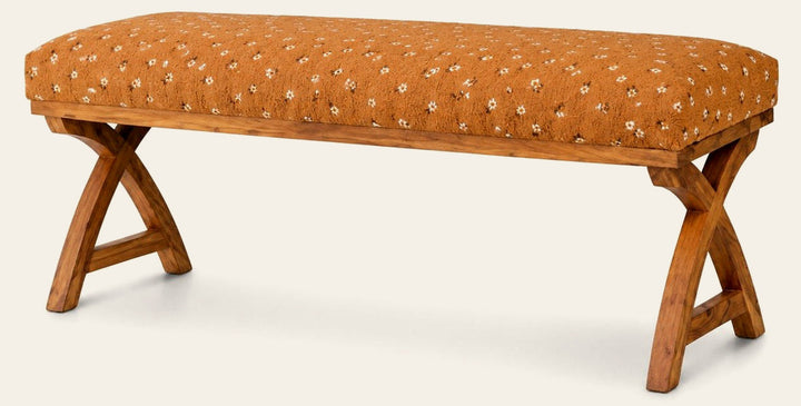 Kalalou upholstered bench with warm patterned fabric and crossed wooden supports on a white studio background.