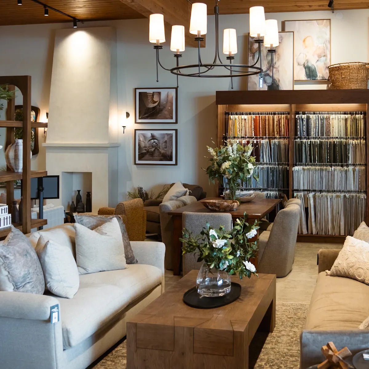 A cream sofa and wood coffee table under a candle chandelier, with the Cedar Mill fabric library and a plaster fireplace behind